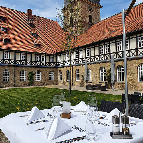 Im Vordergrund ist ein gedeckter Tisch zu sehen im Innenhof des Klosters Wöltingerode, das heute das Klosterhotel beherbergt, zu sehen.