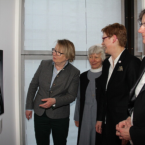 Drei Äbtissinnen und eine Konventualin betrachten ein Schwarz-Weiß-Portrait einer Äbtissin im großen Ornat.