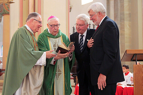 Vier Männer, darunter Klosterkammer-Präsident Hans-Christian Biallas, betrachten ein Buch.