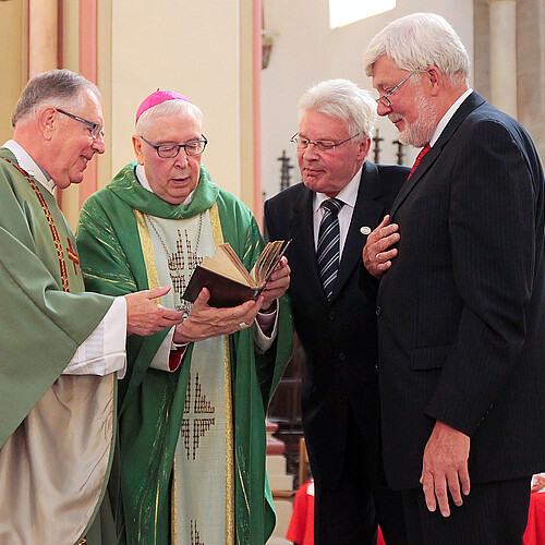 Vier Männer, darunter Klosterkammer-Präsident Hans-Christian Biallas, betrachten ein Buch.