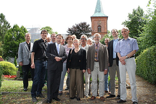 Eine Gruppe von Personen, darunter Andreas Hesse, Kammerdirektor der Klosterkammer, stehen vor einer Kirche.