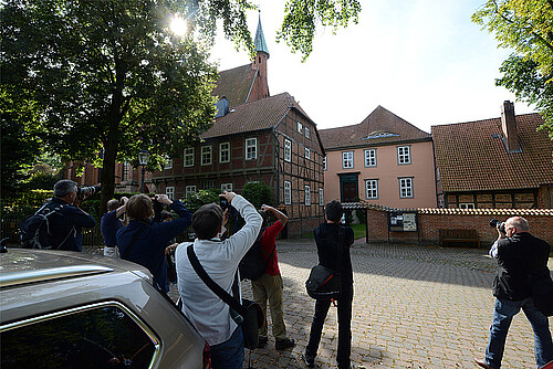 Mehrere Personen sind von hinten zu sehen, sie fotografieren ein historisches Gebäude.