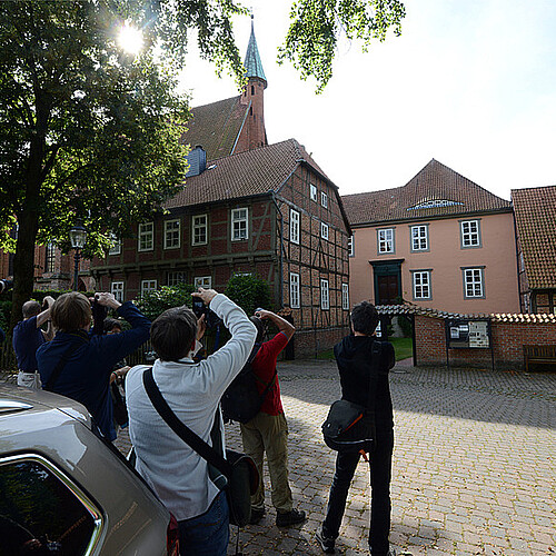 Mehrere Personen sind von hinten zu sehen, sie fotografieren ein historisches Gebäude.