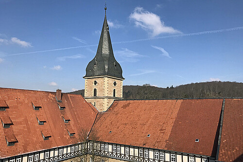 Dachflächen mit roten Dachziegeln des Klosterhotels sowie der in Kirchturm in Wöltingerode sind zu sehen.