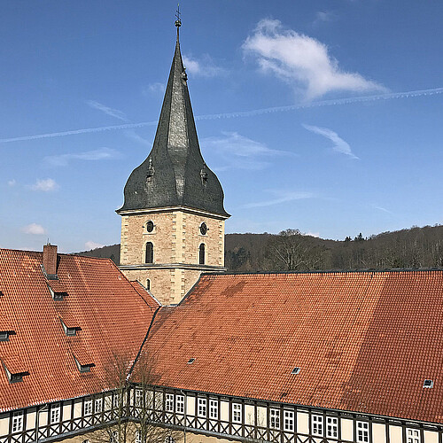 Dachflächen mit roten Dachziegeln des Klosterhotels sowie der in Kirchturm in Wöltingerode sind zu sehen.