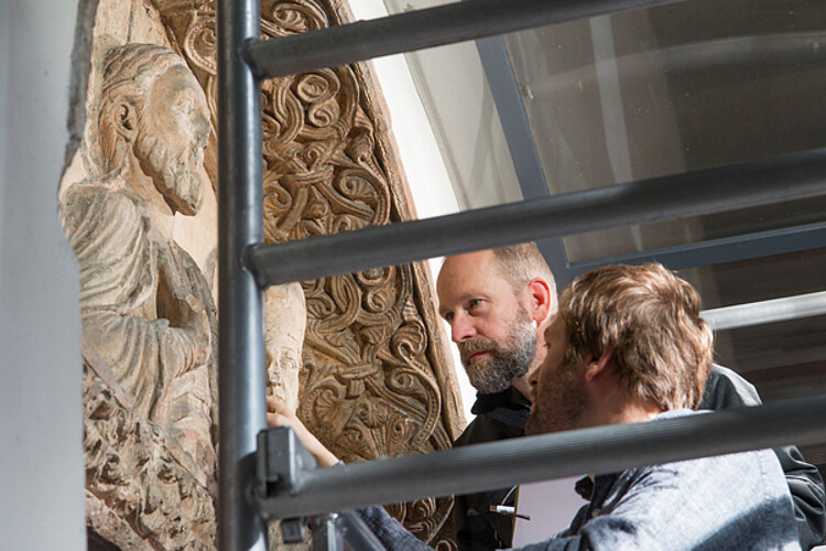 Zwei Frauen in der Textil´restaurierungswerkstatt Lüneburg der Klosterkammer sind über ein Werk gebeugt, tragen beide Handschuhe und haben Pinzetten in der Hand.
