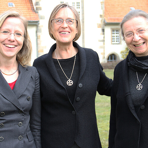 Drei Frauen stehen in dem Innenhof eines Klosters.