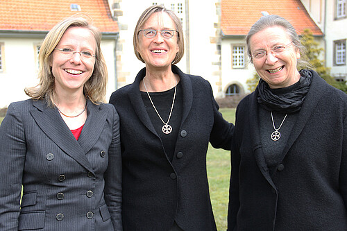 Drei Frauen stehen in dem Innenhof eines Klosters.