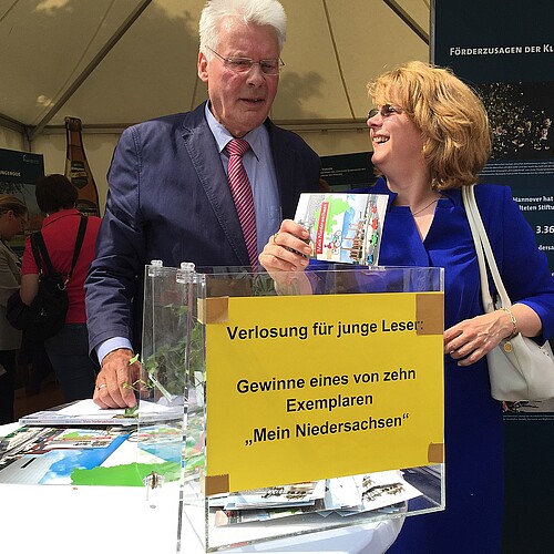 Tag der Niedersachsen 2015: Eine Frau und ein Mann, darunter Klosterkammer-Präsident Hans-Christian Biallas, stehen hinter einer Los-Box.