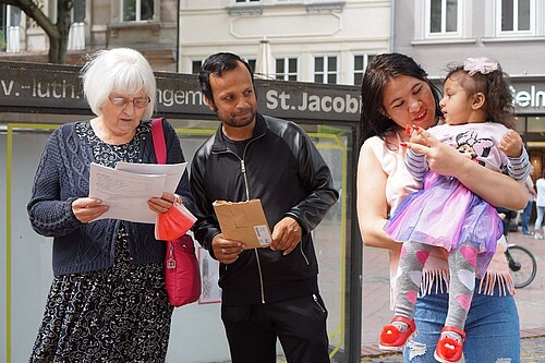 ältere Frau mit junger Familie mit Vater, Mutter und kleiner Tochter; Familie hat Migrationshintergrund