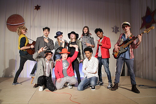 Eine Gruppe Jugendlicher in Kostümen präsentiert sich auf einer Bühne.