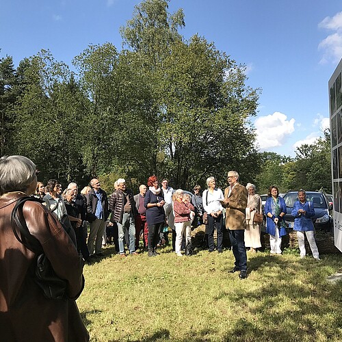 Viele Menschen stehen vor einer Bildtafel.