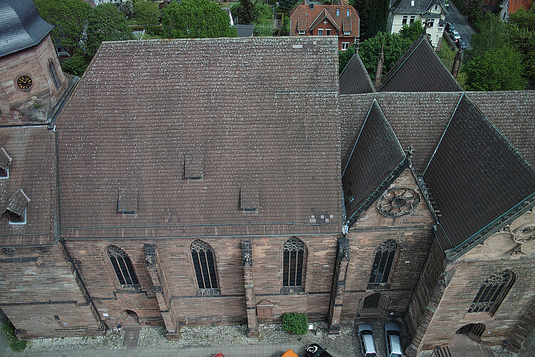 Luftbild auf Kirche. Braun gedecktes Kirchendach. Kirchturm teilweise sichtbar.
