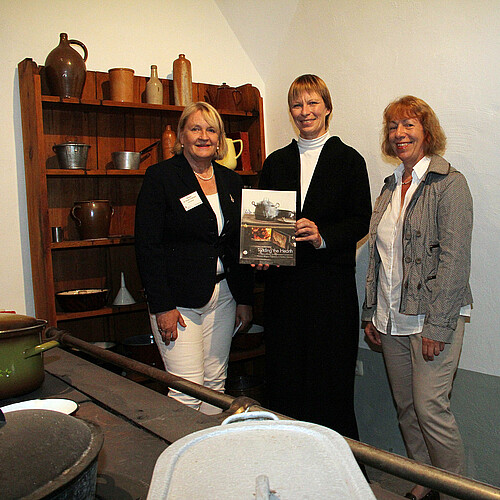 Drei Frauen halten ein Buch.