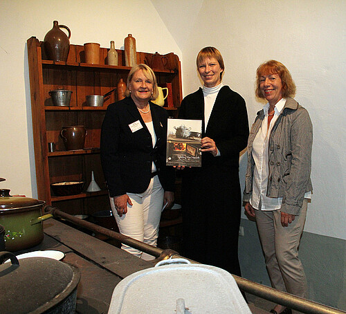 Drei Frauen halten ein Buch.