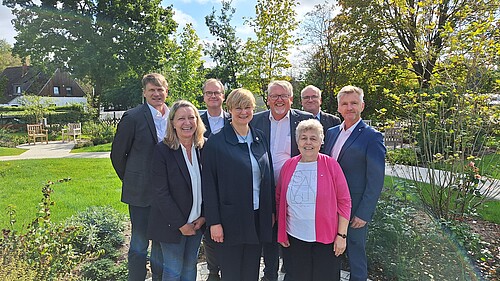 Gruppenbild mit fünf Männern und drei Frauen in einem Park bei Sonnenschein