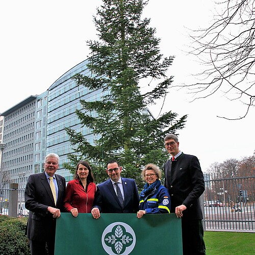 Fünf Personen stehen vor einer Tanne geschmückt mit einer Lichterkette und halten ein Banner mit der Aufschrift Klosterforsten.