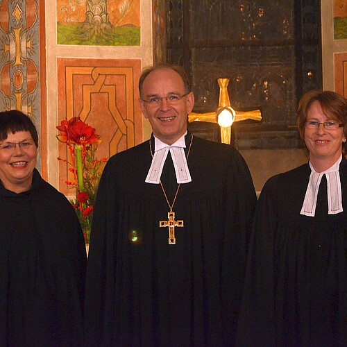 Zwei Frauen, darunter Rosemarie Meding, Äbtissin des Kloster Marienwerder, und ein Mann stehen vor dem Altar der Klosterkirche Marienwerder.
