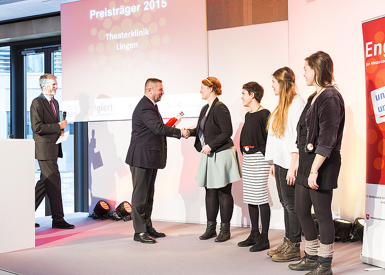 Ein Mann übergibt einer Gruppe von Frauen einen Preis.