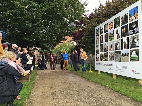 Eine Gruppe von Personen, darunter Schwester Reinhild von Bibra, Äbtissin des Klosters Wülfinghausen, steht vor einer Fotowand zum Workshop Click im Kloster.