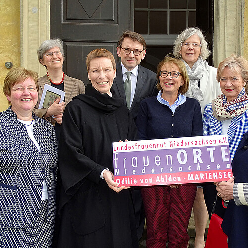 Sieben Damen und ein Herr, Andreas Hesse, Kammerdirektor der Klosterkammer, stehen vor einer hölzernen Eingangstür.