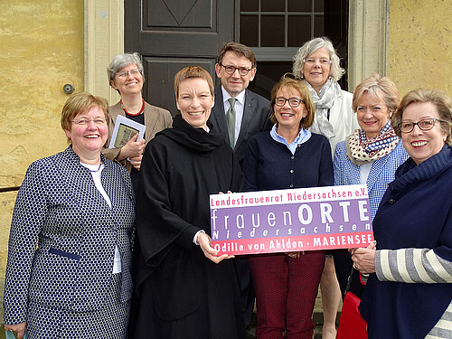 Sieben Damen und ein Herr, Andreas Hesse, Kammerdirektor der Klosterkammer, stehen vor einer hölzernen Eingangstür.