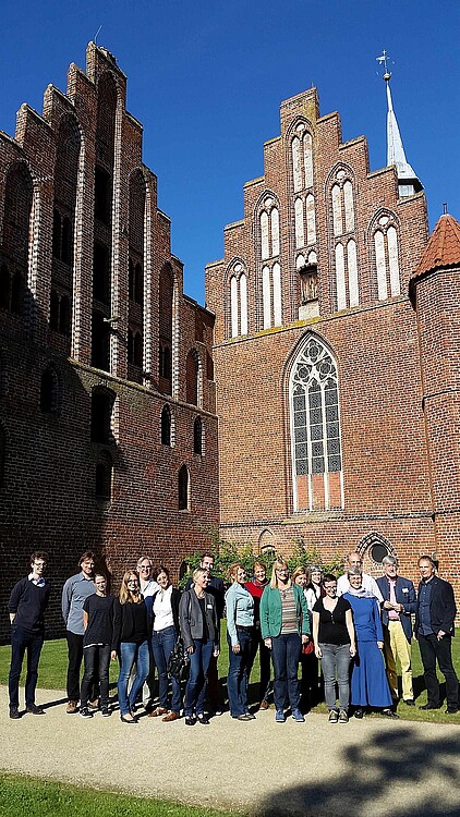 18 Personen stehen vor dem charakteristischen Stufengiebel des Klosters Wienhausen, darunter Kloster-Archivar Wolfgang Brandis.