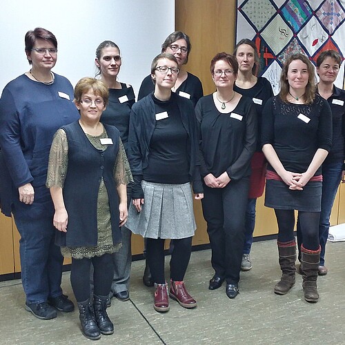 Neun Frauen stehen in zwei Reihen hintereinander.