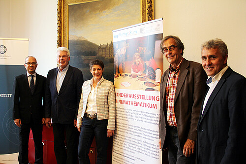 Vier Männer und eine Frau stehen neben einem Roll-up.