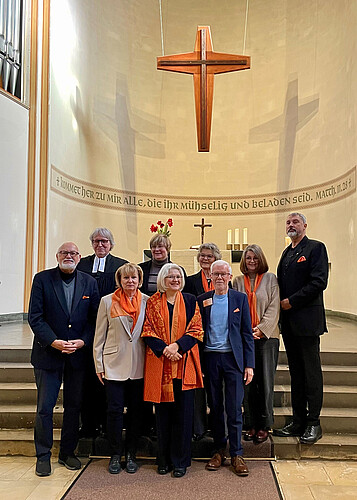 Neun Personen stehen vor dem Altar in einer Kirche.