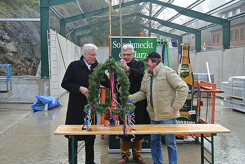 Drei Herren stehen um einen mit bunten Bändern geschmückten Richtkranz, darunter Klosterkammer-Präsident Hans-Christian Biallas.