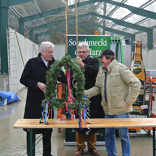 Drei Herren stehen um einen mit bunten Bändern geschmückten Richtkranz, darunter Klosterkammer-Präsident Hans-Christian Biallas.