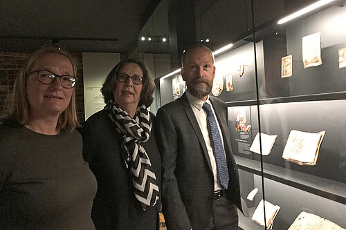 Drei Personen stehen in einen Ausstellungsraum des neuen Klostermuseums Wienhausen neben einer Vitrine.