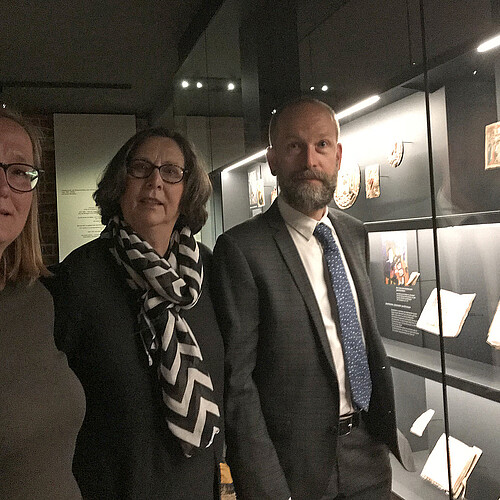Drei Personen stehen in einen Ausstellungsraum des neuen Klostermuseums Wienhausen neben einer Vitrine.