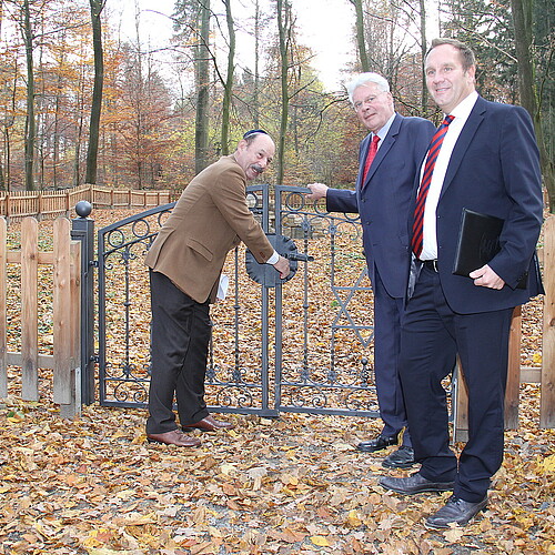 Drei Männer, darunter Klosterkammer-Präsident Hans-Christian Biallas, stehen vor einem Tor.