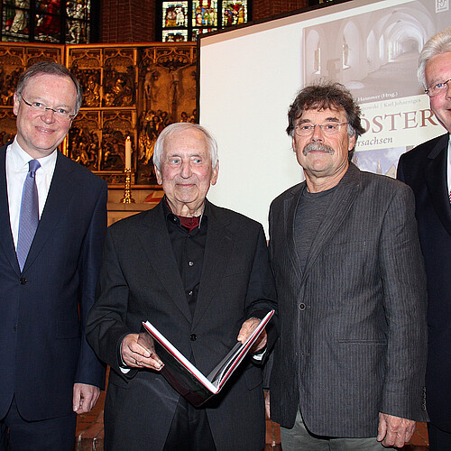 Vier Männer, darunter Klosterkammer-Präsident Hans-Christian Biallas, präsentieren den Bildband „Klöster in Niedersachsen“ in der Marktkirche.