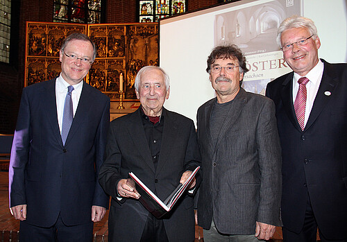 Vier Männer, darunter Klosterkammer-Präsident Hans-Christian Biallas, präsentieren den Bildband „Klöster in Niedersachsen“ in der Marktkirche.