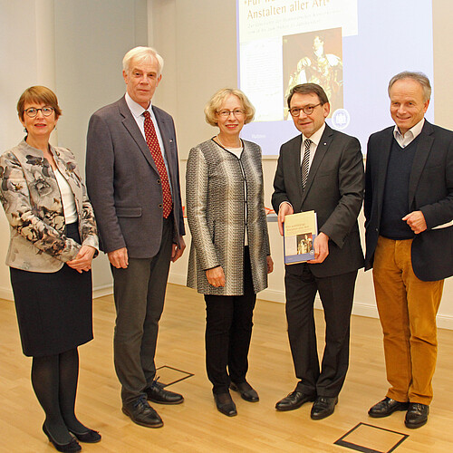 Zwei Frauen und drei Männer stehen nebeneinander in einem Vortragssaal.
