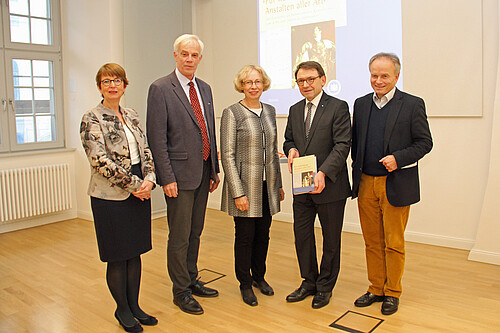 Zwei Frauen und drei Männer stehen nebeneinander in einem Vortragssaal.