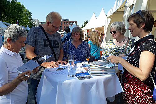 Eine Gruppe steht rund um einen Tisch mit Büchern und Flyern zur Klosterkammer Hannover.