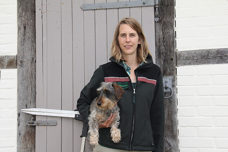 Frau mit Dackel vor der Tür eines Fachwerkhauses