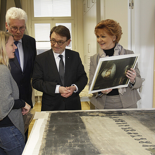 Zwei Frauen und zwei Männer stehen in der Restaurierungswerkstatt der Klosterkammer an einem Tisch.