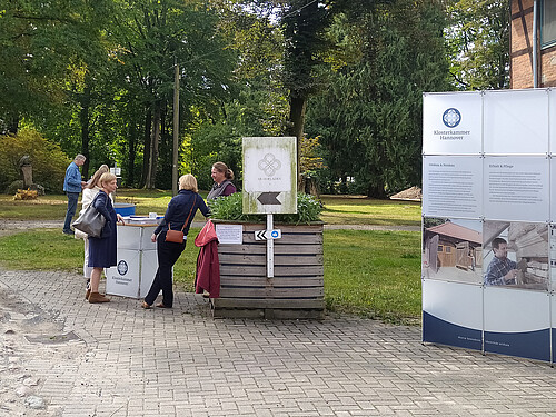 Gutspark Burgsittensen, Menschen stehen an Stehtisch, Infowand