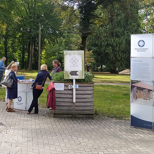 Gutspark Burgsittensen, Menschen stehen an Stehtisch, Infowand