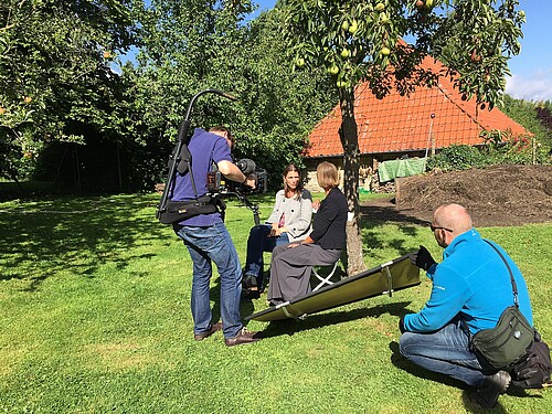 Ein Kamerateam filmt zwei Frauen, darunter Schwester Reinhild von Bibra, Äbtissin des Klosters Wülfinghausen, im Garten unter einem Birnenbaum.