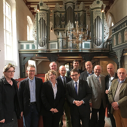 Eine Gruppe von Frauen und Männern, darunter Kammerdirektor Andreas Hesse, stehen in dem Mittelgang der Kirche St. Johannis in Oederquart. Im Hintergrund ist eine kunstvoll gestaltete historische Orgel zu sehen.