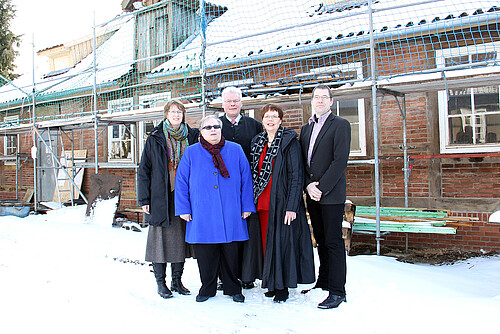Drei Frauen und zwei Männer, darunter Klosterkammer-Präsident Hans-Christian Biallas, Rosemarie Meding, Äbtissin im Kloster Marienwerder, und Dr. Tim Wameling, Baudezernent der Klosterkammer Hannover, stehen vor einem eingerüsteten Gebäude  des Klosters Marienwerder im Schnee.