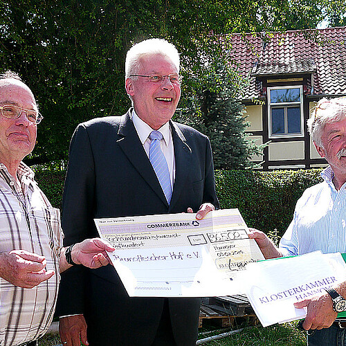 Drei Männer, darunter Klosterkammerpräsident Hans-Christian Biallas, halten einen übergroßen symbolischen Scheck.