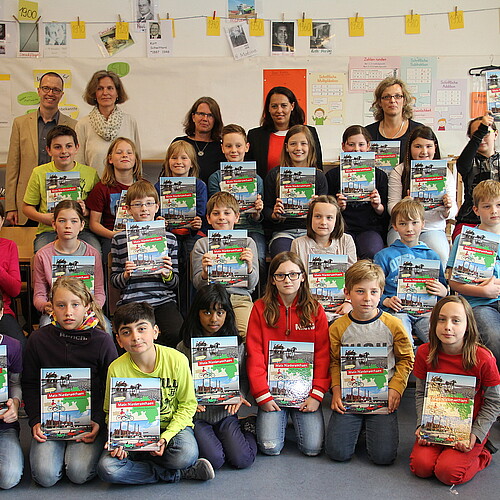 Eine Gruppe von Kindern und Erwachsenen, darunter Anna Mohr, Dezernentin in der Abteilung Förderungen der Klosterkammer, halten ein Buch in der Hand.