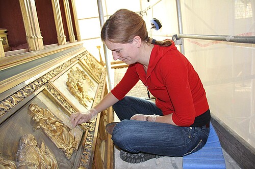 Hochaltar im Dom Verden: Eine Frau sitzt vor einem goldenen Relief.